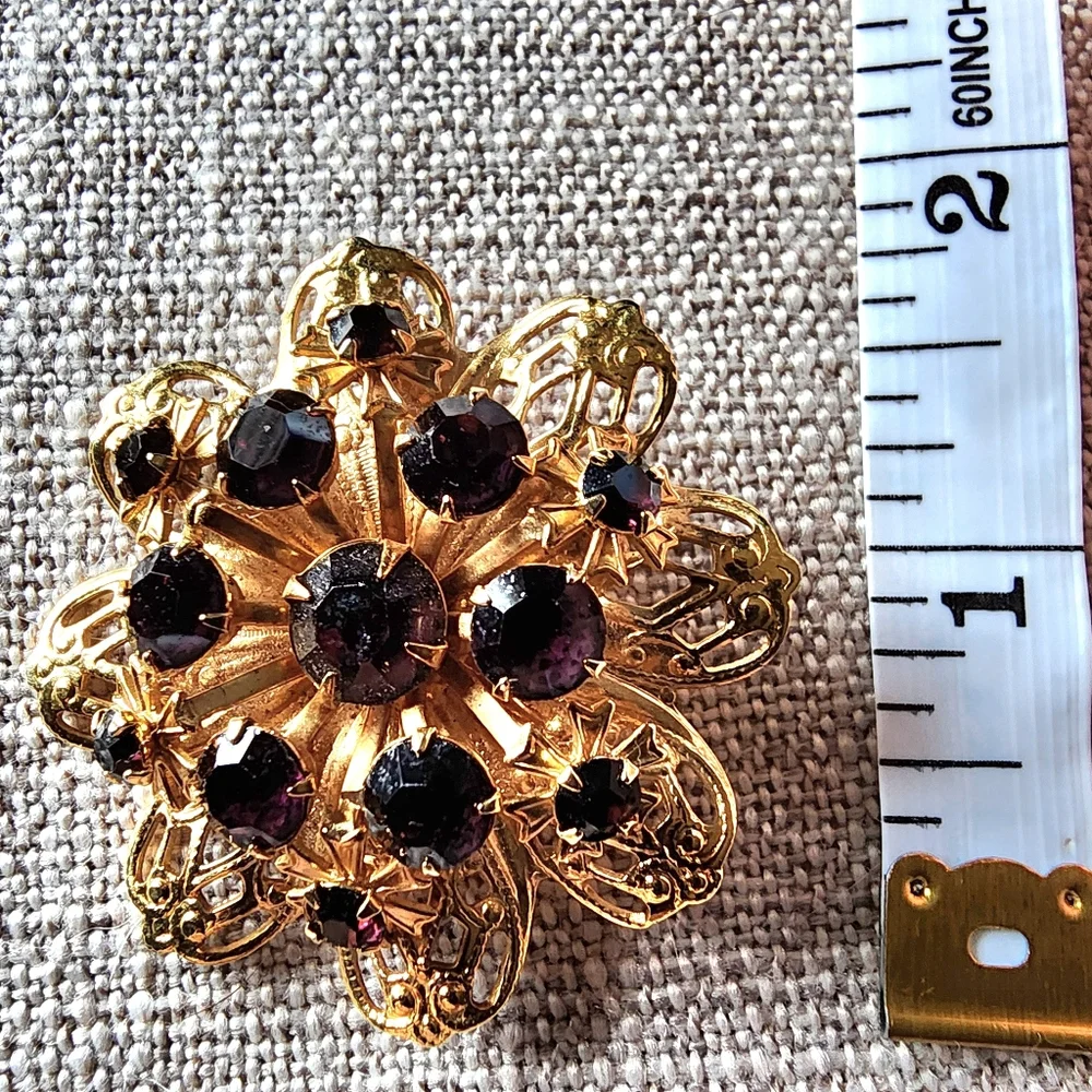 Vintage gold-toned round floral pin/brooch w/ deep violet rhinestones. 1960's
